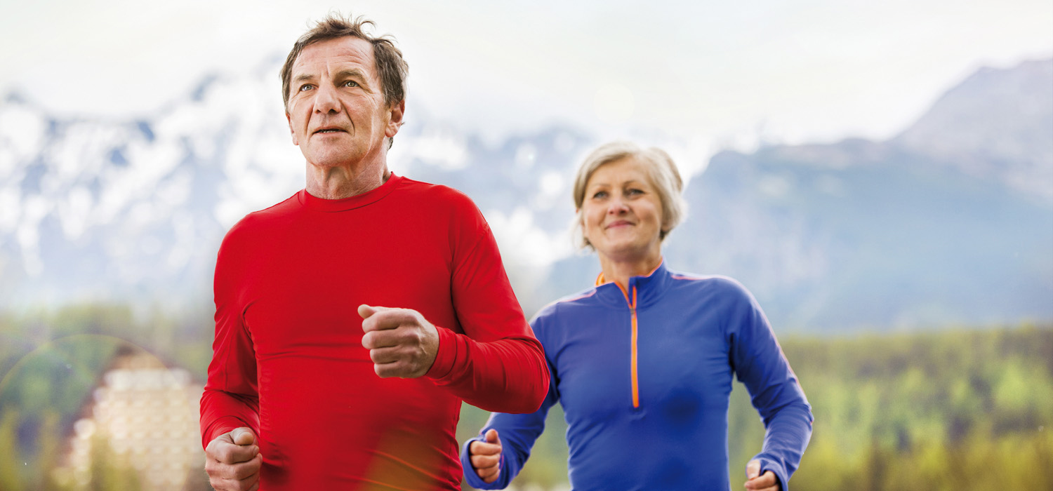 Älteres Ehepaar joggt gemeinsam durch die Natur und hält sich fit.