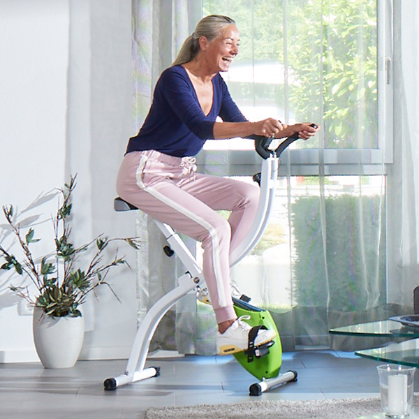 Frau höheren Alters trainiert zuhause auf einem Fitnessgerät.