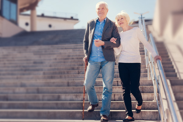 Mann mit Gehstock geht eine Treppe herunter