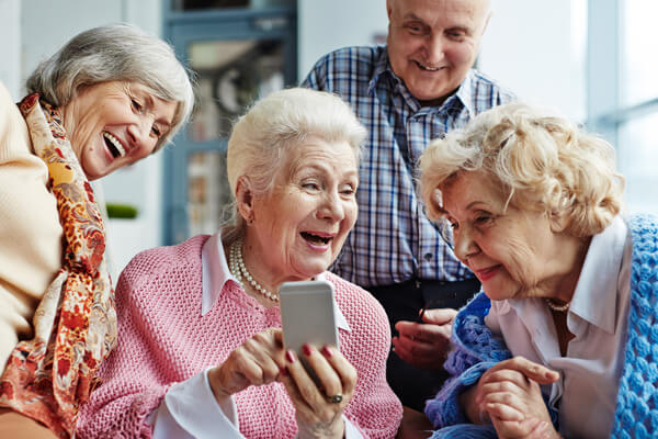 Eine Gruppe älterer Damen schaut belustigt auf ein Mobiltelefon.