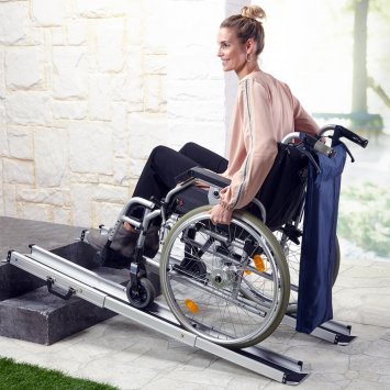 Rollstuhlfahrerin fährt über eine Rollstuhlrampe die Treppe hoch