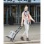 Schlanke Frau mittleren Alters posiert mit einem Einkaufsroller, auf dem ein Kasten Wasser steht